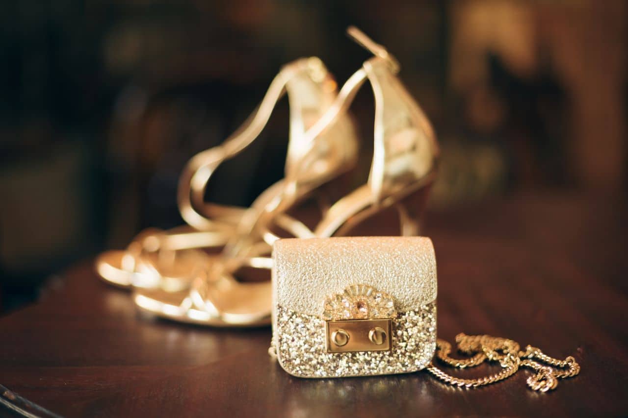 Imagem de sapato de salto dourado e bolsa dourada que remetem ao luxo